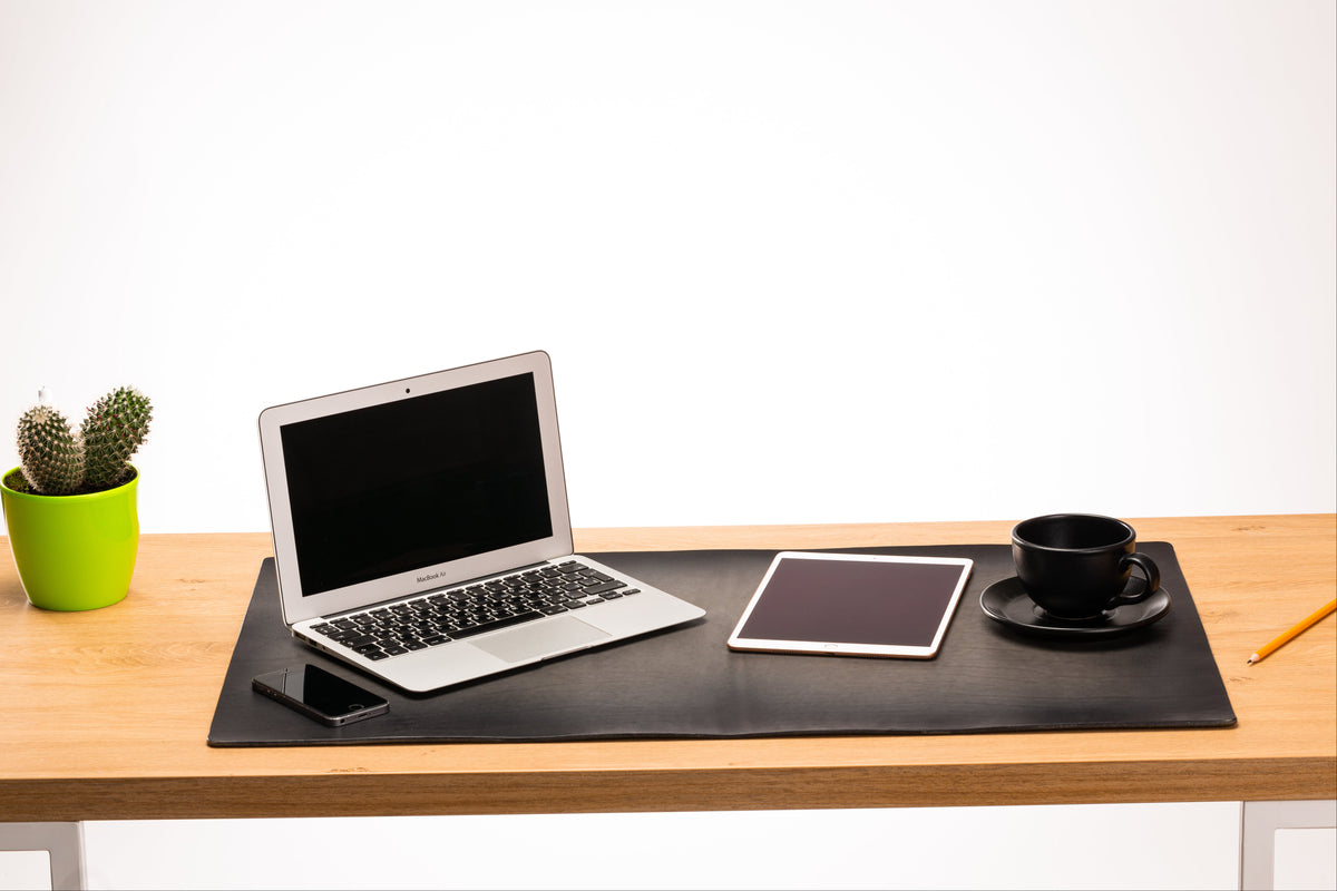 Large gray leather executive desk pad with hand-painted dark perimeter on natural wood desk