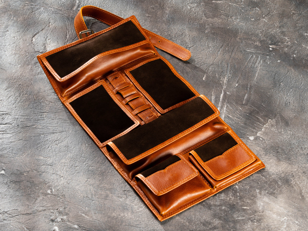Camel roll-up leather travel organizer opened to display compartments for small essentials and accessories