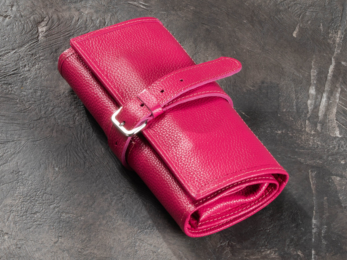 1. Closed Raspberry Pink leather roll-up travel organizer with adjustable buckle strap