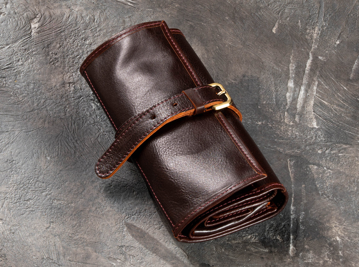 Closed Dark Brown leather roll-up travel organizer with adjustable buckle strap and brass hardware