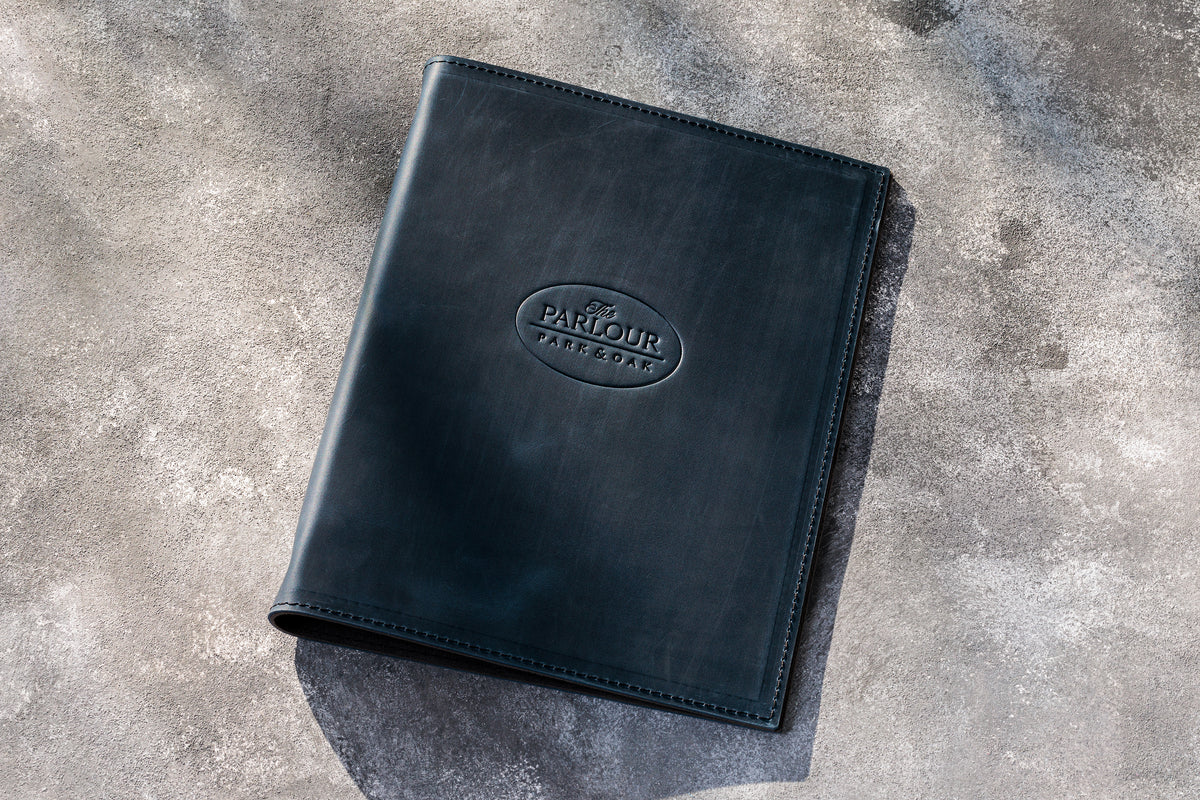 Dark blue leather restaurant menu binder with custom embossed logo and stitched edges
