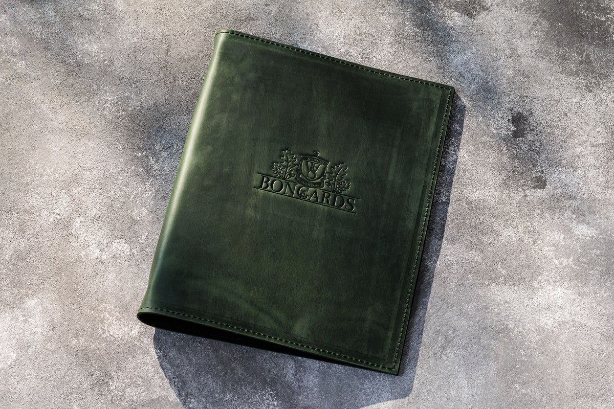 Dark green leather restaurant menu binder with custom embossed logo and 3-ring construction