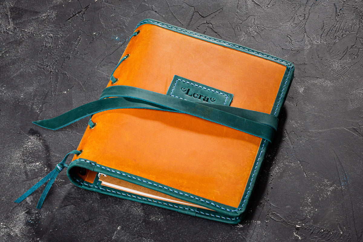 Closed wheat yellow leather journal cover with teal trim, wrap strap and personalized name tag
