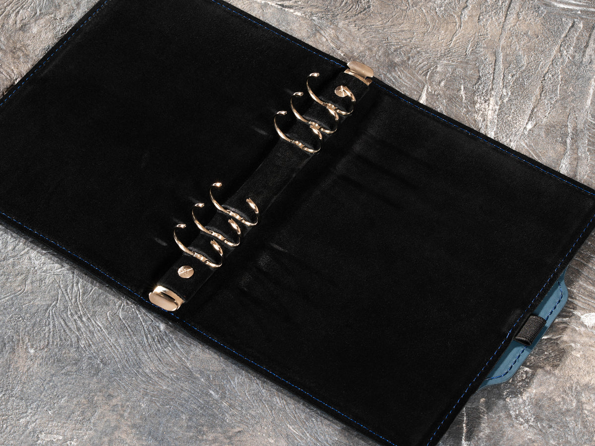 Open Slate Blue leather notebook showing six-ring mechanism and black suede interior