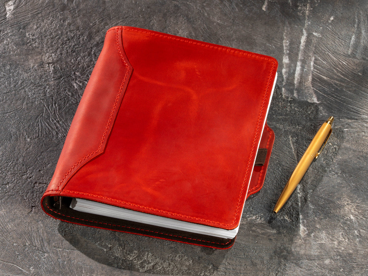 Red refillable leather business notebook with gold pen beside the cover