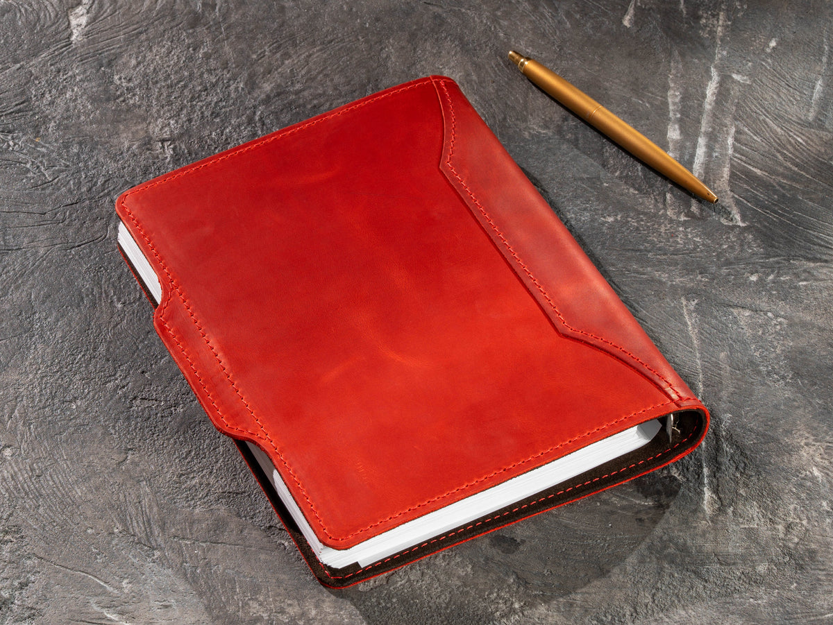 Open red leather refillable notebook with lined pages and ring mechanism