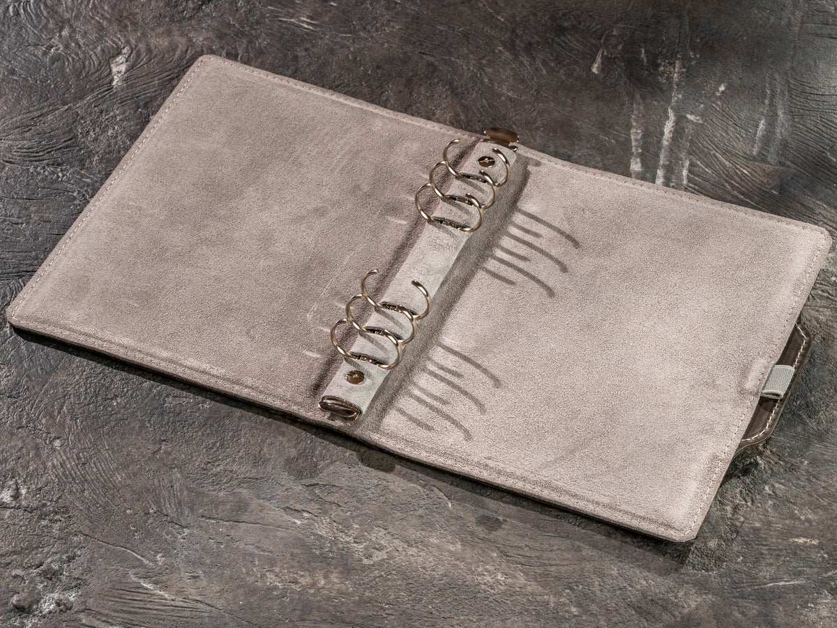 Interior of gray leather refillable business notebook showing ring mechanism and suede lining