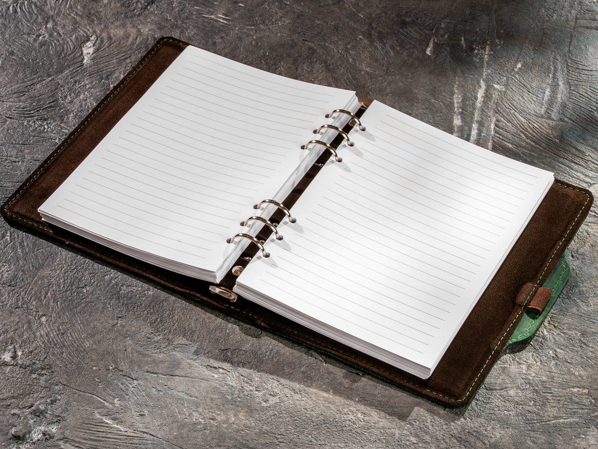 Open green leather business notebook with refillable lined pages and ring mechanism