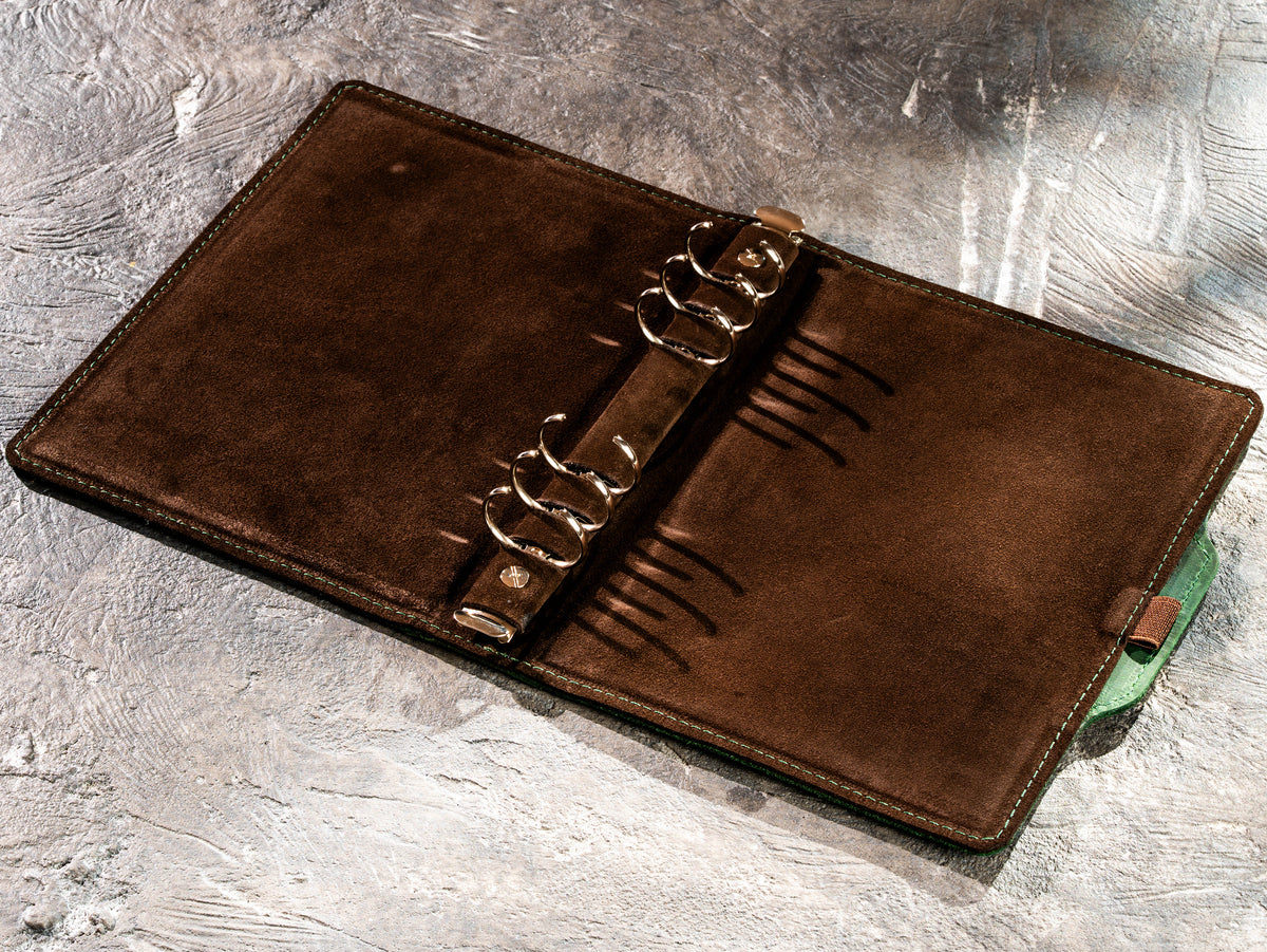 Interior of green leather refillable notebook showing ring mechanism and suede lining
