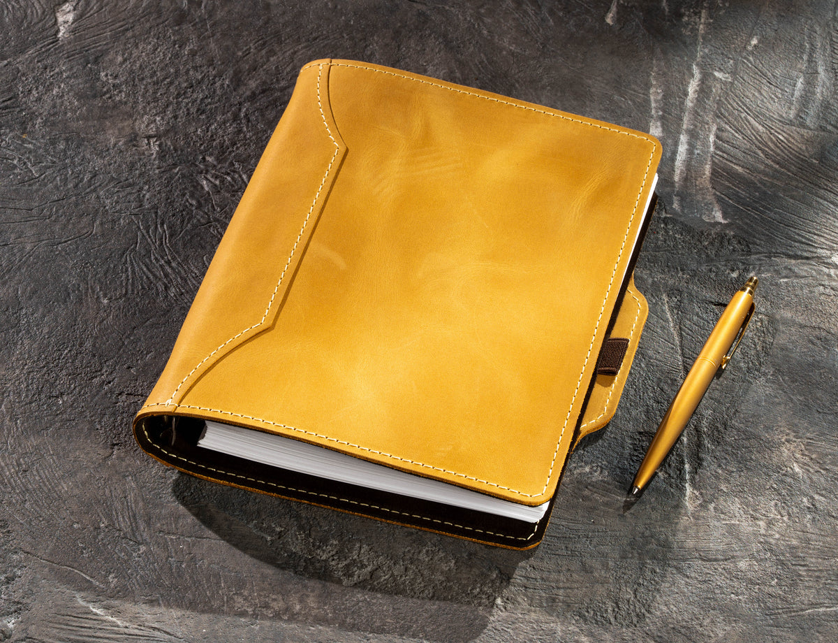 Yellow leather business notebook with gold pen beside the cover, refillable A5 and 8.5 x 5.5 format