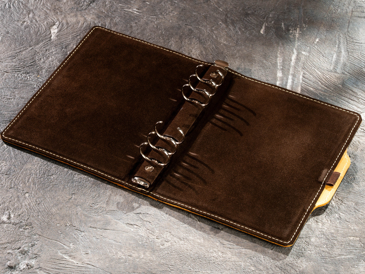 Interior of yellow leather A5 and 8.5 x 5.5 notebook showing six-ring binder mechanism and suede lining