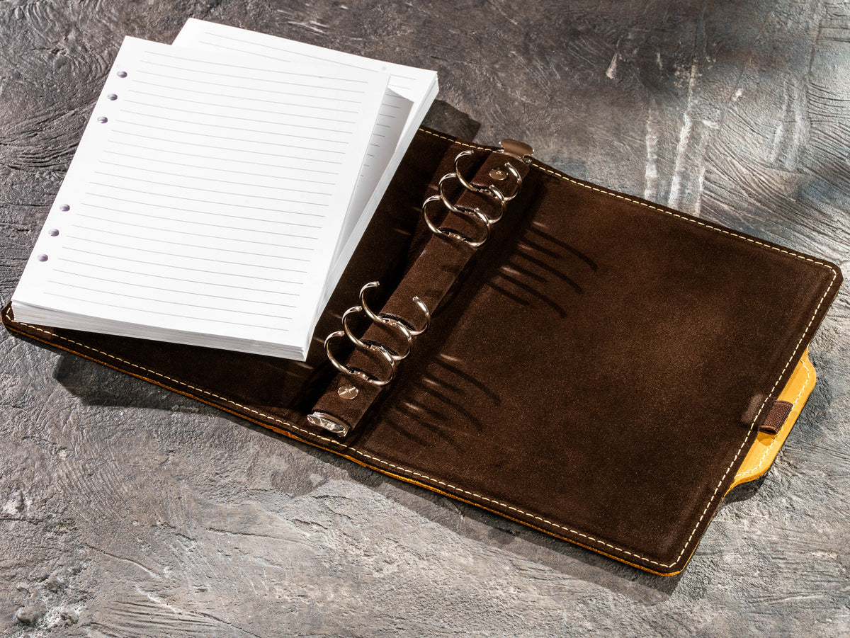 Refillable yellow leather business notebook with removable lined paper inserts and six-ring binding system