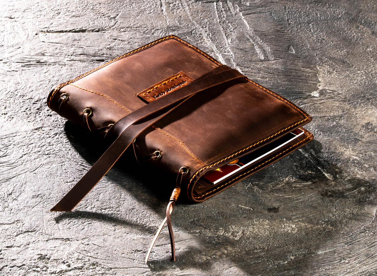 Closed brown leather artist organizer for A5 and 8.5 x 5.5 sketchbooks with wrap strap and sample personalized name tag